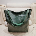 Gros plan détaillé d'un grand sac fourre-tout vert en similicuir sur un canapé beige - Type standard / Vert