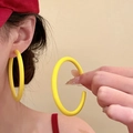 Gros plan d'une mannequin portant de grandes créoles en acrylique jaune au style estival - Jaune-Grandes Boucles d'Oreilles Créoles