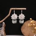 Ethnic style silver peacock bell tassel earrings displayed on a natural branch - Silver Hollow Peacock(E2043-5)