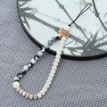 Detail of beaded phone strap featuring marble beads and turquoise wooden charm - Black & White Fire Agate + Bodhi Bead Style