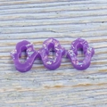 Macro detail of three purple resin Hamsa hands with colorful opal glitter on wood - Purple