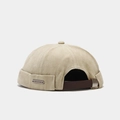 Détail du bonnet docker rétro kaki avec sangle en cuir et plaque de marque argentée - Réglable / Poche zippée