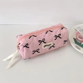 Dettaglio dell'astuccio rosa trapuntato con fiocchi stampati su scrivania bianca - Fiocco Nero