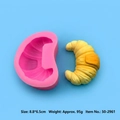 Pink silicone croissant mold with finished yellow candle specimen on blue surface - Croissant-50-2961-A