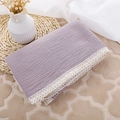 Nahaufnahme einer lila Musselin-Babydecke mit feiner weißer Häkelspitze am Rand - Violettblau