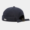 Detail of navy blue docker hat featuring a small white fox embroidery and metal buckle - Adjustable / Dark Gray
