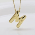 Detailed close-up of golden letter M bubble pendant with bamboo texture on a necklace - Letter M (Necklace)