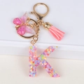 Glittery resin letter K keychain with pink butterfly pendant and tassel accessory - Letter K