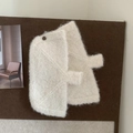 Close-up of white plush knitted glove accessories with buttons on cork background - Off White