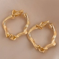 Makro-Detail von goldenen geometrischen Creolen mit gedrehter Textur auf Seidenhintergrund - Goldene Ohrringe mit S925 Silbernadel / Gold