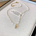Elegante gouden ketting met witte rijstkralen en schelphanger op beige dienblad - Ketting-Wit-Wulk