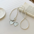 Collier de perles élégant avec pendentifs cœurs argentés sur fond blanc artistique - Bandoulière en perles