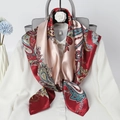 Detail eines roten Paisley-Satinschals, drapiert über ein weißes Hemd und Tasche - Rot