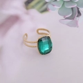 Gros plan d'une bague dorée ornée d'une grande pierre carrée vert émeraude et anneau ouvert - Ouvert Réglable