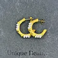 Detail of vintage 18k gold C-shape bamboo earrings with pearls on a dark stone background - Bamboo Joint Pearl