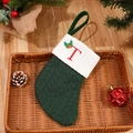 Green knitted Christmas stocking with red embroidered letter T and holly leaf detail - Letter T