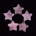 Detailed view of five natural pink crystal star-shaped stones on a dark surface - Rose Quartz
