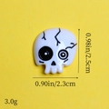 Dettaglio del ciondolo a teschio in resina con dimensioni 2,5 cm altezza e 2,3 cm larghezza su giallo - Teschio Bianco Vene Nere