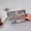 Handheld blue and gold jacquard floral makeup bag with metal zipper and woven label - Flowing Blue Small
