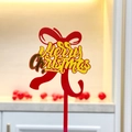 Close-up of a red acrylic Merry Christmas cake topper with golden script lettering - Red Gold Bow Merry Christmas