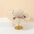 Beige wide brim straw hat with fringe edge and bow decoration on a gold display stand - M (56-58cm) / Beige