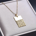 Macro d'un pendentif rectangulaire doré avec une finition lisse et texturée unique - Collier Or