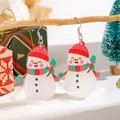 Detailed close-up of resin snowman earrings with festive glitter on a Christmas branch - Snowman