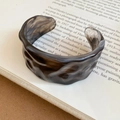 Macro shot of irregular smoky marble resin cuff bracelet on an open art book - Wide Irregular Open Design / Grey Smoky Marble
