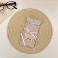 Close-up of floral fabric glasses pouch with blue snap button and pink ribbon bow detail - Colorful Floral