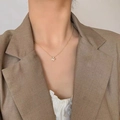 Dettaglio della collana con pendente a farfalla dorata indossata da una modella in abito - Argento 925 / Oro