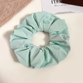 Detailed view of a soft light green ruffled scrunchie with a smooth fabric texture - Green