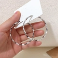 Große silberne gedrehte Creolen mit elegantem Spiraldesign auf weißer Schmuckkarte - Verdrehte große Creolen / Silber
