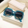 Detailed macro view of square glitter sunglasses on elegant white gift boxes - Green Frame Green Tea Lens