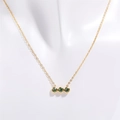 Dettaglio collana dorata con tre pietre natali verdi orizzontali su un manichino bianco - Agosto (Verde)