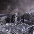 Detailed close-up of matte black spider web cuff bracelet on dark stone surface - Black