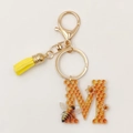 Detail of Letter M acrylic honeycomb keychain with gold lobster clasp and yellow tassel - Letter M