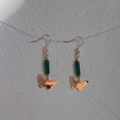 Detail of 18K gold butterfly earrings with green natural stone beads on a textured surface - Butterfly Shape with Green Stone (060 Butterfly)