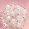 Vue macro de perles d'étoiles irisées de 16mm avec visages souriants dans un bol en verre - Étoile Smiley Blanche / 16mm Lumineux