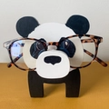 Creative panda shaped wooden glasses holder with tortoiseshell frames on a yellow surface - Panda