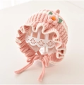 Detailed view of pink knitted baby bonnet with ruffled edges and floral accents - 3M-2Y / Pink