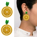 Detailed view of orange slice acrylic earrings with glitter yellow finish and green leaves - Lemon Slice