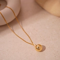 Vista macro dettagliata di una collana con ciondolo a sfera dorata su una superficie in pietra - Oro