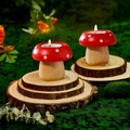 Set of two mushroom candles with red polka dot caps on rustic wood bases in a forest setting - Mushroom Shape