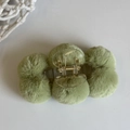 Close-up of a green plush ball hair claw clip with transparent plastic and gold spring - Green