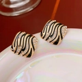 Macro-opname van vierkante zebra oorbellen met gouden basis en kristallen op plateau - 4# Zebraprint Geometrische Strass Oorknopjes