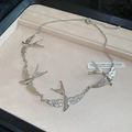 Macro shot of silver swallow bird links necklace on beige velvet jewelry display - Necklace - Silver