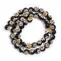 Makroaufnahme von spiralig angeordneten schwarzen Millefiori-Glasperlen mit Blumendesign - Durchmesser 6mm Länge 35cm ca. 55 Stück / Schwarz Gelbe Blume