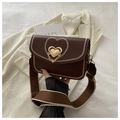 Detail of dark brown saddle bag featuring heart metal lock and stylish wide strap - Coffee