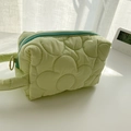 Dettaglio della trousse trapuntata verde chiaro con cuciture floreali e zip blu - Verde