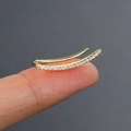 Golden curved ear crawler featuring rows of white cubic zirconia held on fingertips - Gold (Ear Crawler)